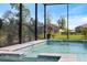 Inviting screened-in pool with a ledge and tropical plants providing shade at 16131 Poplar Hill Ln, Port Charlotte, FL 33953