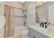 Bathroom with a shower-tub combo with gray tile, white cabinets, and neutral paint at 18135 Home Run Dr, Venice, FL 34293