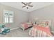 Charming bedroom featuring two twin beds, a ceiling fan, and a bright window with shutters at 18135 Home Run Dr, Venice, FL 34293