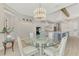 Elegant dining area featuring a glass table, modern chandelier, and seamless access to a white kitchen at 18135 Home Run Dr, Venice, FL 34293