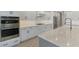 Modern white kitchen featuring stainless steel appliances, a gas range, and a large island with a sink at 18135 Home Run Dr, Venice, FL 34293