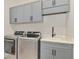 Laundry room with modern appliances, gray cabinets, and a sink for added convenience at 18135 Home Run Dr, Venice, FL 34293