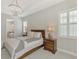 Comfortable main bedroom with tray ceilings, a crystal chandelier, and a window with wooden shutters at 18135 Home Run Dr, Venice, FL 34293