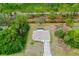 Expansive aerial view of a charming home with a long driveway surrounded by lush greenery and mature trees at 1893 Amato St, North Port, FL 34291