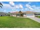 Charming single-story home with a well-manicured lawn, vibrant landscaping, and a welcoming blue front door at 1915 Pebble Beach Ct, Venice, FL 34293