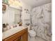 Well-lit bathroom featuring wood cabinets, a marble shower curtain, and decorative shelving at 19248 Isadora St, Venice, FL 34293