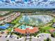 Aerial view showcasing the community pool, tennis courts, and lake at 20420 Symphony Pl, Venice, FL 34293
