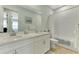 Bright bathroom featuring double vanity, bathtub with shower, and white cabinets at 20420 Symphony Pl, Venice, FL 34293