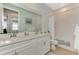 Bright bathroom featuring double vanity, bathtub with shower, and white cabinets at 20420 Symphony Pl, Venice, FL 34293