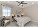 Stylish bedroom featuring a ceiling fan, bed with blue pillows, a woven chair, and natural light at 20420 Symphony Pl, Venice, FL 34293