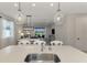 The kitchen island overlooks the living area and features pendant lights, bar seating, and a stainless steel sink at 20420 Symphony Pl, Venice, FL 34293