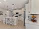 Open kitchen boasts white cabinets, stainless steel appliances, a center island with bar seating, and modern pendant lights at 20420 Symphony Pl, Venice, FL 34293