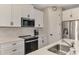 Close-up of a kitchen featuring white cabinets, a stylish backsplash, stainless steel appliances, and quartz countertops at 20420 Symphony Pl, Venice, FL 34293