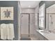 Bathroom shower featuring stone tile flooring, a glass door, white tile, and turtle art at 20420 Symphony Pl, Venice, FL 34293