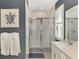 Bathroom shower featuring stone tile flooring, a glass door, white tile, and turtle art at 20420 Symphony Pl, Venice, FL 34293