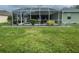 View of a screened-in lanai and backyard with green grass and small plants at 2115 Pan American Blvd, North Port, FL 34287