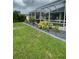 View of a screened-in lanai and backyard with green grass and plants around the edge at 2115 Pan American Blvd, North Port, FL 34287