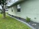 Exterior view of a one-story house, with a well maintained lawn, some shrubbery and decorative rocks at 2115 Pan American Blvd, North Port, FL 34287