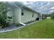 Side exterior view of home with manicured lawn and tropical foliage at 2115 Pan American Blvd, North Port, FL 34287