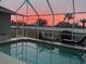 Enclosed pool area with beautiful sunset view and comfortable lounge chairs at 2115 Pan American Blvd, North Port, FL 34287