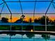 Sparkling pool with a screened enclosure overlooking a colorful sunset backdrop at 2115 Pan American Blvd, North Port, FL 34287