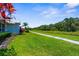 Lush green backyard with a walking path and tropical landscaping against a clear sky at 213 Venice Palms Blvd, Venice, FL 34292