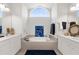Large bathroom featuring double vanities, tiled bath surround, and a bright arched window at 213 Venice Palms Blvd, Venice, FL 34292