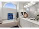 Bright bathroom with double vanity, soaking tub, and an arched window providing natural light at 213 Venice Palms Blvd, Venice, FL 34292