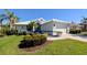 Charming home exterior featuring well-maintained landscaping, lush green lawn, and a white tile roof at 213 Venice Palms Blvd, Venice, FL 34292