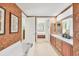 Bright bathroom boasts double vanity with soaking tub, decorative wallpaper and tile floors at 23138 Copperleaf Dr, Venice, FL 34293