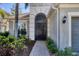 View of home's entry showcasing a black decorative security door, paver walkway, and lush landscaping at 23138 Copperleaf Dr, Venice, FL 34293
