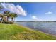 Lush grassy waterfront view with blue skies, fluffy white clouds, and tranquil waters at 23138 Copperleaf Dr, Venice, FL 34293