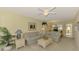 Bright living room featuring neutral carpet, ceiling fan, and comfortable blue furniture at 310 Lynbrook Cir # 103, Venice, FL 34292