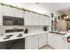 Bright kitchen featuring white cabinets, black appliances and tile flooring at 3300 Loveland Blvd # 1201, Punta Gorda, FL 33980