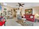 Bright living room with a ceiling fan, a red leather sofa, dining area and large windows providing ample natural light at 3300 Loveland Blvd # 1201, Punta Gorda, FL 33980