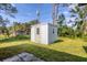 A charming white backyard shed with a grey door, sitting on a lush green lawn at 3716 Dunbar Rd, Venice, FL 34293