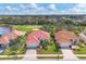 This aerial view showcases a well-maintained home with a red tile roof, manicured lawn, and beautiful landscaping at 446 Pinewood Lake Dr, Venice, FL 34285