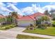 Beautiful single-story home featuring a red tile roof, a two-car garage, lush landscaping, and a well-manicured lawn at 446 Pinewood Lake Dr, Venice, FL 34285