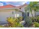 A well-maintained home featuring a red tile roof, a two-car garage, and lush landscaping at 446 Pinewood Lake Dr, Venice, FL 34285