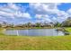 Scenic view of a pond surrounded by lush landscaping and residential homes at 446 Pinewood Lake Dr, Venice, FL 34285