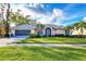Well-maintained single-Gathering home featuring lush landscaping and a spacious front lawn at 5051 Greenway Dr, North Port, FL 34287
