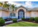 Welcoming front entrance with arched doorway, complemented by beautiful landscaping at 5051 Greenway Dr, North Port, FL 34287