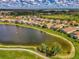 Wide aerial shot showcasing neighborhood homes lining a tranquil pond with lush greenery at 5151 Pine Shadow Ln, North Port, FL 34287