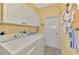 Laundry room with modern washer and dryer with bright yellow walls and ample storage at 5151 Pine Shadow Ln, North Port, FL 34287