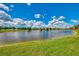 Beautiful pond view with a well-maintained grassy bank and a clear sky dotted with white clouds at 5151 Pine Shadow Ln, North Port, FL 34287