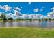 Picturesque pond with clear water and a grassy shoreline under a bright blue sky with scattered clouds at 5151 Pine Shadow Ln, North Port, FL 34287