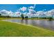 Scenic pond view surrounded by lush green grass and mature trees on a sunny day at 5151 Pine Shadow Ln, North Port, FL 34287