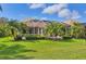 Backyard view of lush landscaping, a screened-in patio, and mature palm trees at 560 Misty Pine Dr, Venice, FL 34292