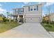Two-story home features a neutral exterior, blue shutters, a two-car garage, and a front porch at 5767 Woodland Sage Dr, Sarasota, FL 34238