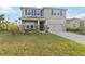 Two-story home features a neutral exterior, blue shutters, a two-car garage, and a charming front porch at 5767 Woodland Sage Dr, Sarasota, FL 34238